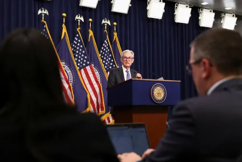 رئيس الاحتياطي الفيدرالي جيروم باول يتحدث في مؤتمر صحفي، مع العلم الأمريكي خلفه، وسط اهتمام الإعلام بتوجهات السياسة النقدية.