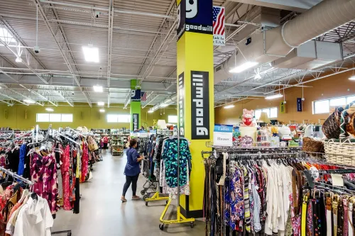 متجر Goodwill يعرض مجموعة متنوعة من الملابس والأغراض، حيث يعمل فيه شخص يتسوق بين الرفوف. يُظهر الصورة أهمية برامج العمل لكبار السن.