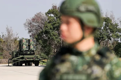 جندي يرتدي خوذة عسكرية أمام نظام دفاع صاروخي في تايوان، مما يعكس الاستعدادات العسكرية amid التوترات مع الصين.