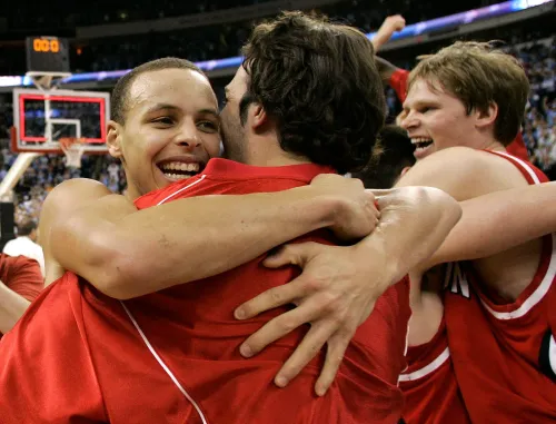 لاعبو كرة السلة يحتفلون بفوزهم في مباراة حاسمة، مع التركيز على ستيف كوري، الذي أظهر أداءً مميزًا في البطولة NCAA.