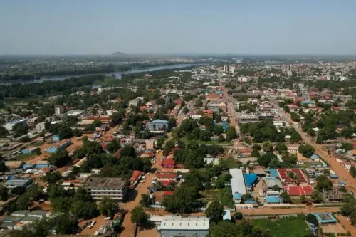 منظر جوي لمدينة جوبا في جنوب السودان، يظهر المباني والطرق والأشجار، مع نهر يمر عبر المنطقة، مما يعكس الأوضاع الحالية في البلاد.