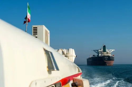 سفينة شحن إيرانية تحمل علم إيران، تبحر في المياه، مما يبرز تأثير العقوبات الأمريكية على صادرات النفط الإيراني.