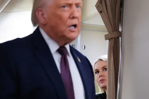 صورة لترامب يتحدث في مؤتمر صحفي، بينما تظهر مساعدته كارولين ليفيت خلف الستارة، تعكس التوترات حول تصريحاته المثيرة للجدل بشأن الانتخابات.