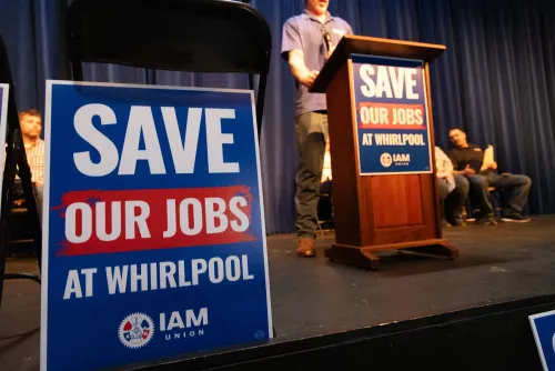 لافتة كبيرة تحمل عبارة "أنقذوا وظائفنا في ويرلبول" خلال حدث نقابي، تعكس القلق بشأن تسريح العمال في صناعة الأجهزة.