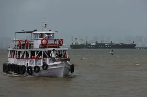 قارب صغير يبحر في المياه مع سفينة كبيرة في الخلفية، يمثل حركة الشحن الحيوية في مضيق هرمز وسط التوترات الإقليمية.