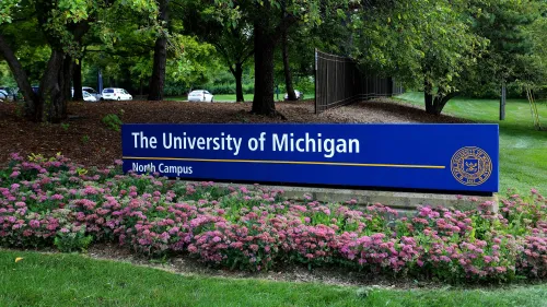 لافتة جامعة ميشيغان في الحرم الشمالي، محاطة بأزهار ملونة، تعكس التغييرات في برامج التنوع والمساواة التي تم الإعلان عنها مؤخرًا.