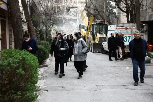 مشهد لشارع في طهران بعد غارة، حيث يسير الناس بحذر وسط الدمار، مع وجود معدات إنقاذ في الخلفية.