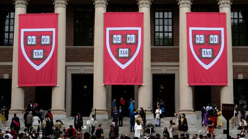 شعار جامعة هارفارد مع طلاب يحتفلون أمام المبنى الرئيسي، مما يعكس أهمية التعليم العالي وتأشيرات الطلاب.