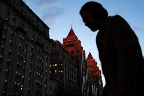 رجل يسير بجوار مبنى صحيفة واشنطن بوست، حيث تظهر الأضواء في النوافذ مع غروب الشمس، مما يعكس التوترات الحالية في غرفة الأخبار.