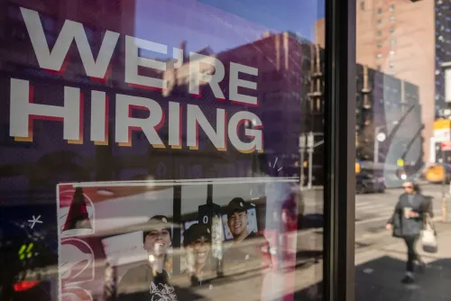 لافتة "نحن نوظف" مع صور لثلاثة موظفين مبتسمين، تعكس حالة سوق العمل في الولايات المتحدة وتوقعات التوظيف لعام 2026.