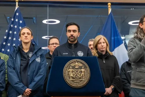 عمدة مدينة نيويورك يتحدث خلال مؤتمر صحفي عن استجابة المدينة للعاصفة الثلجية، محاطًا بفريقه وممثلين عن خدمات الطوارئ.