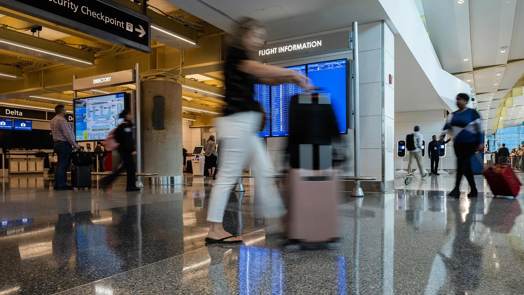 مسافرون في مطار مع معلومات عن الرحلات، يوضحون التباين في أسعار التذاكر بين المسافرين المنفردين والمجموعات.