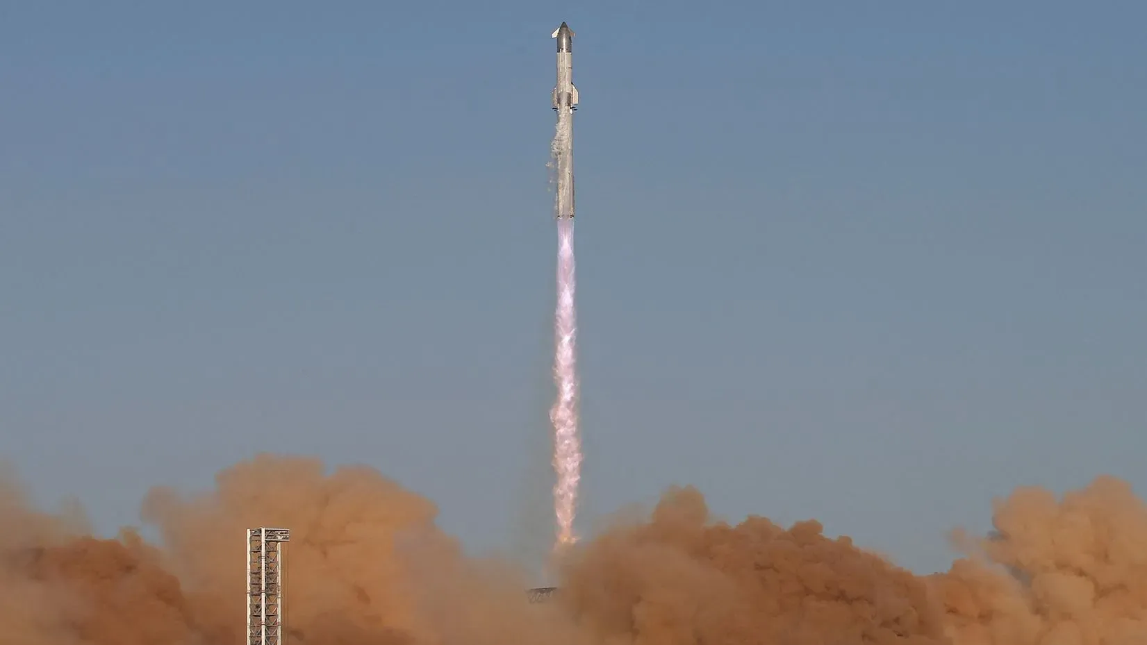 إطلاق مركبة سبيس إكس ستارشيب، مع اشتعال محركاتها، بينما تنطلق نحو السماء وسط سحب من الدخان.