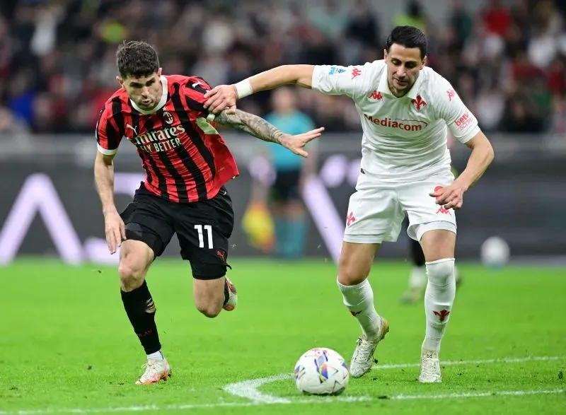 لاعب ميلان كريستيان بوليسيتش يتنافس مع لاعب فيورنتينا خلال مباراة، مع التركيز على الأداء القوي للاعبين الأمريكيين في أوروبا.