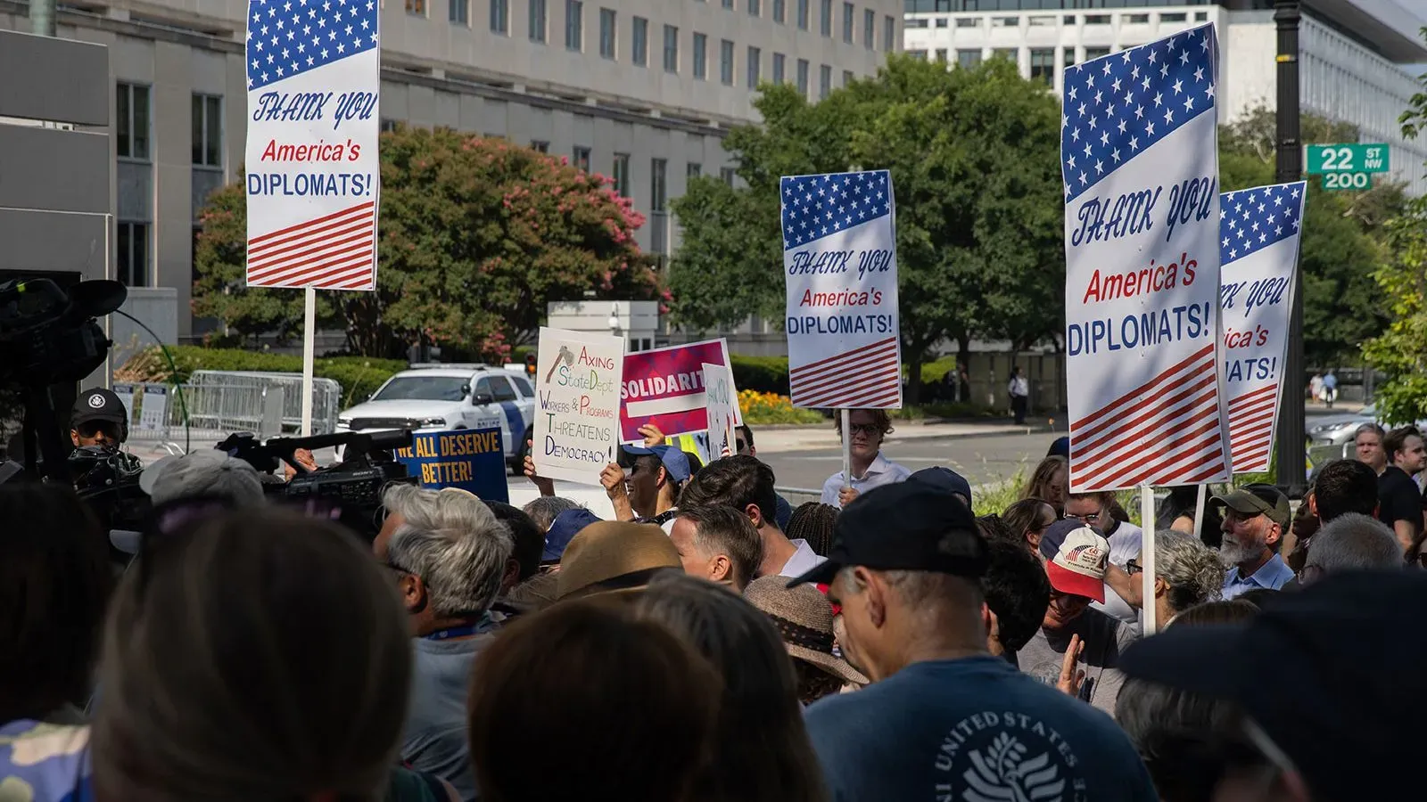 محتجون يحملون لافتات تشكر الدبلوماسيين الأمريكيين، مع تركز الأضواء على القضايا المتعلقة بتخفيضات وزارة الخارجية.