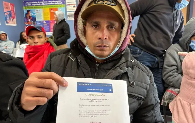 رجل يحمل وثيقة أمامه في مركز للمهاجرين بمدنية سيوداد خواريز، يظهر على وجهه شعور القلق والأمل في الحصول على موعد للهجرة.