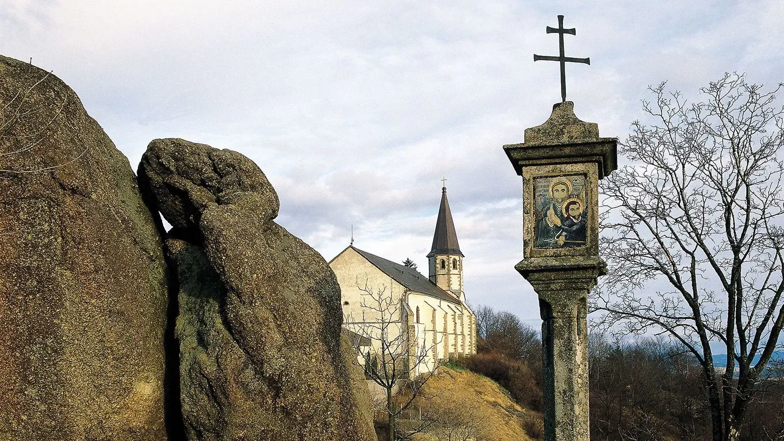 كنيسة سانت توماس آم بلاسينشتاين في جبال الألب، مع صليب وأيقونة دينية، محاطة بالطبيعة، تعكس تاريخ التحنيط الغامض.