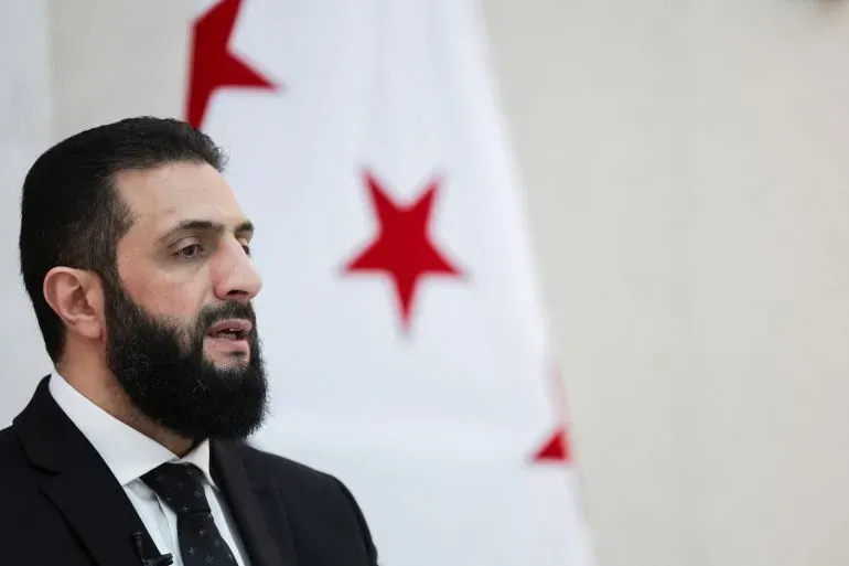 تصريح الرئيس السوري أحمد الشرع حول حماية حقوق الدروز في السويداء، مع خلفية لعلم يحمل النجوم الحمراء.
