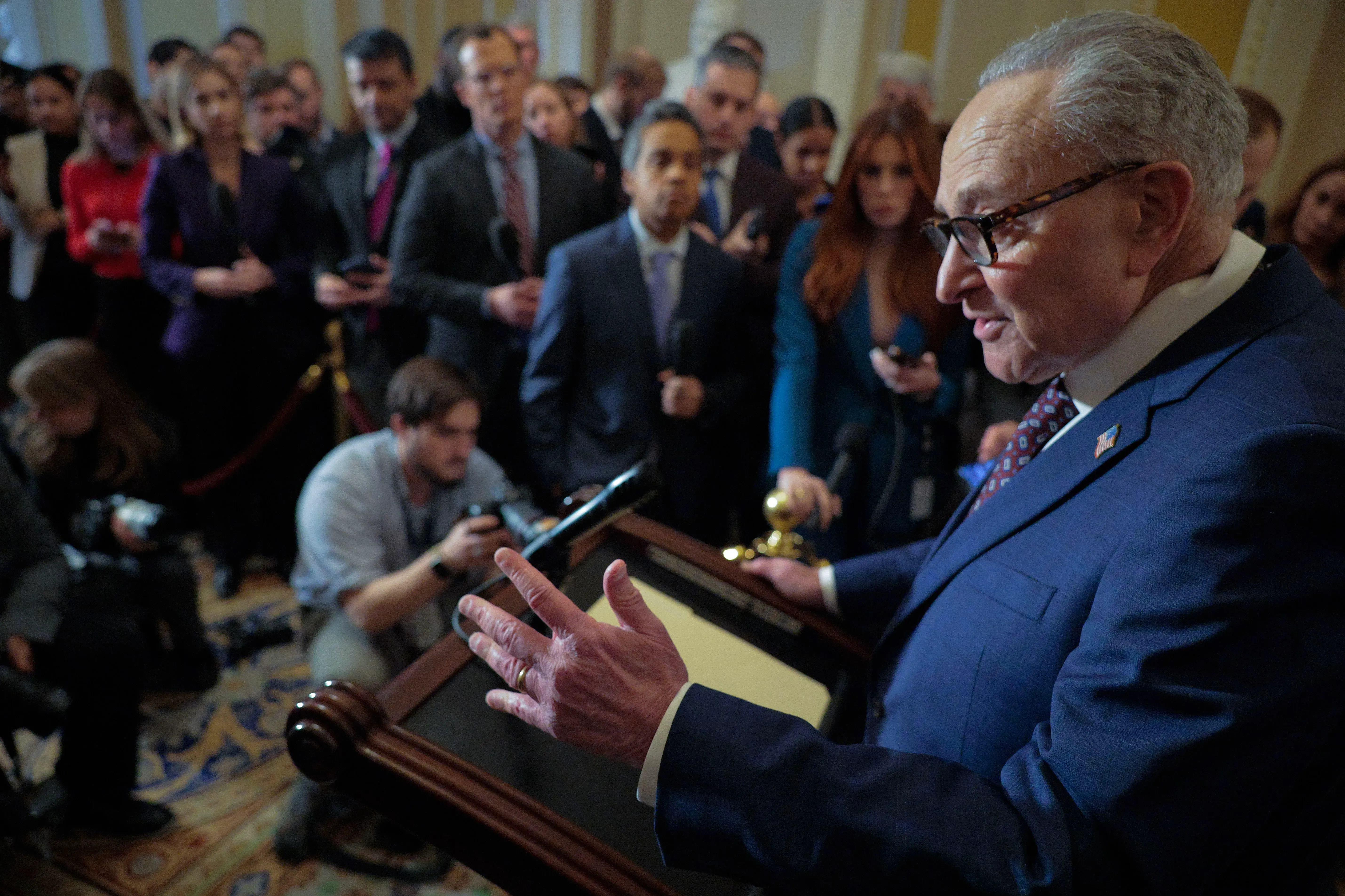 شومر يتحدث أمام حشد من الصحفيين في الكابيتول، مع التركيز على المفاوضات حول تمويل الحكومة وإدارة الهجرة.