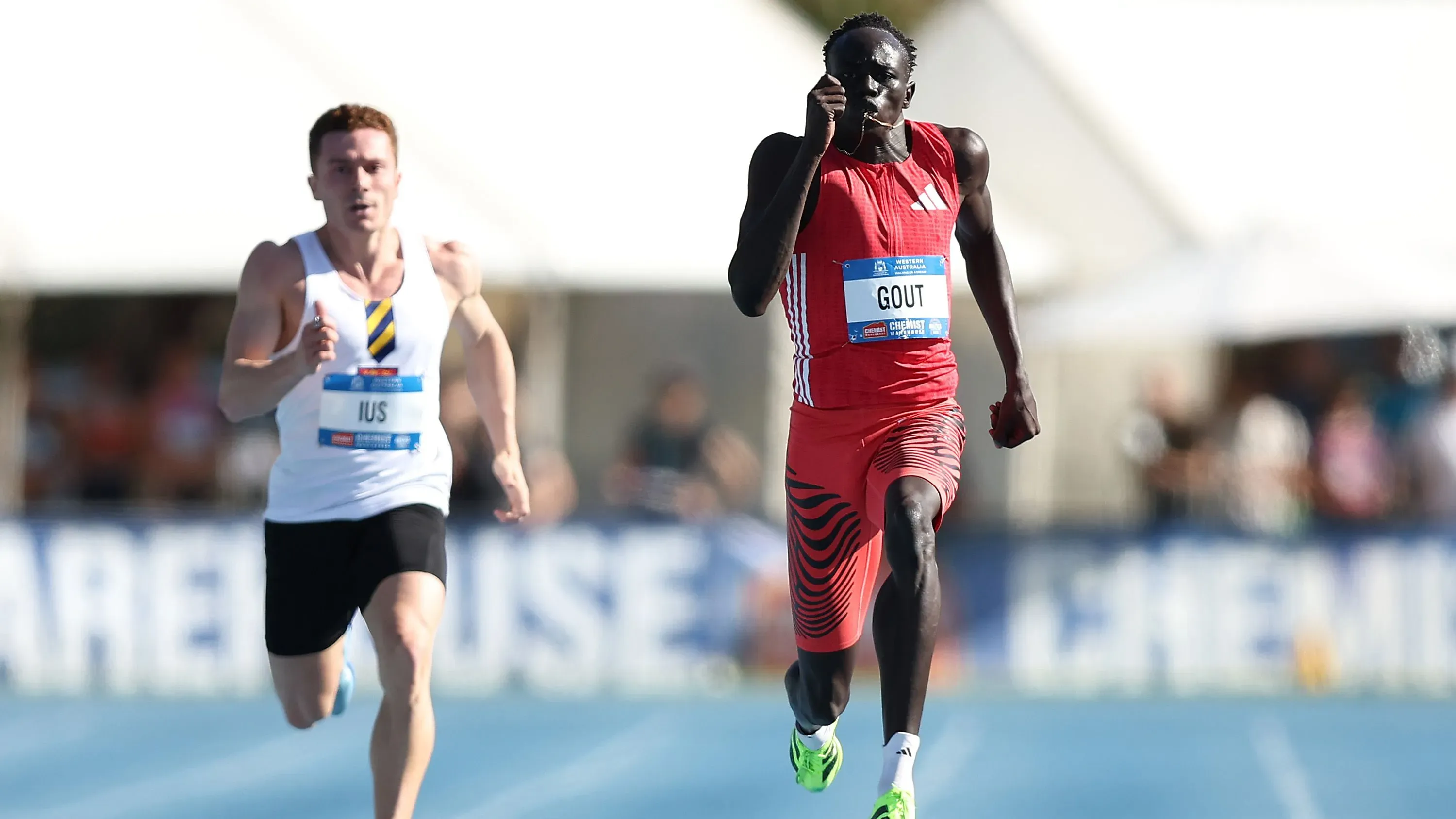 غوت، العداء الأسترالي، يتفوق في سباق 200 متر مرتديًا زيًا رياضيًا أحمر، متقدمًا على منافسه في بطولة أستراليا لألعاب القوى.