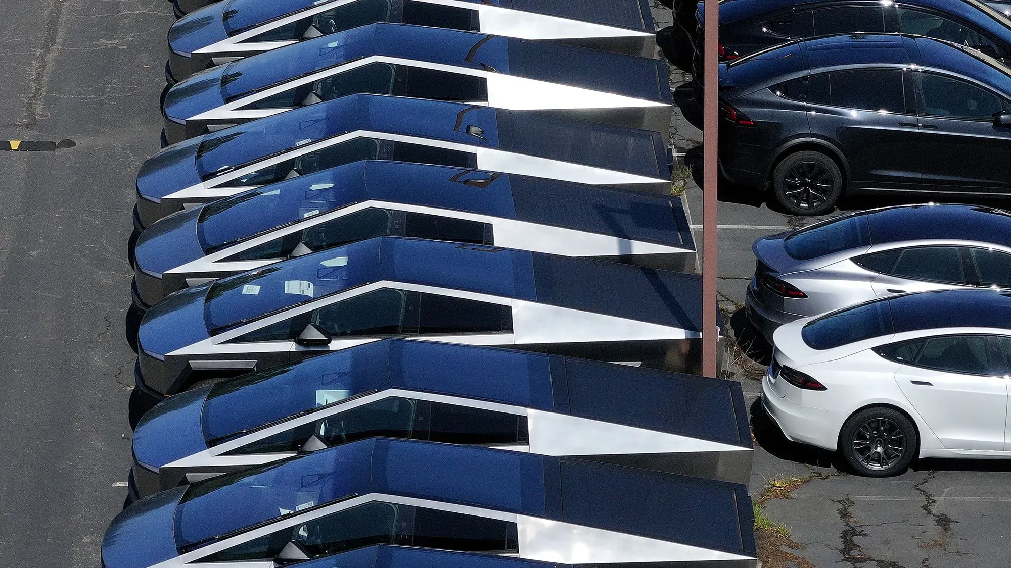 صف من سيارات تسلا الكهربائية ذات التصميم الفريد، مع التركيز على الطراز Cybertruck، في موقف سيارات، مما يعكس التحديات التي تواجهها الشركة في السوق.