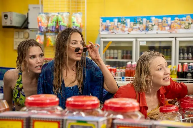 ثلاث صديقات يتبادلن النظرات في متجر، مع أجواء مرحة تعكس تفاعلاتهن في الموسم الثالث من "اللوتس الأبيض".