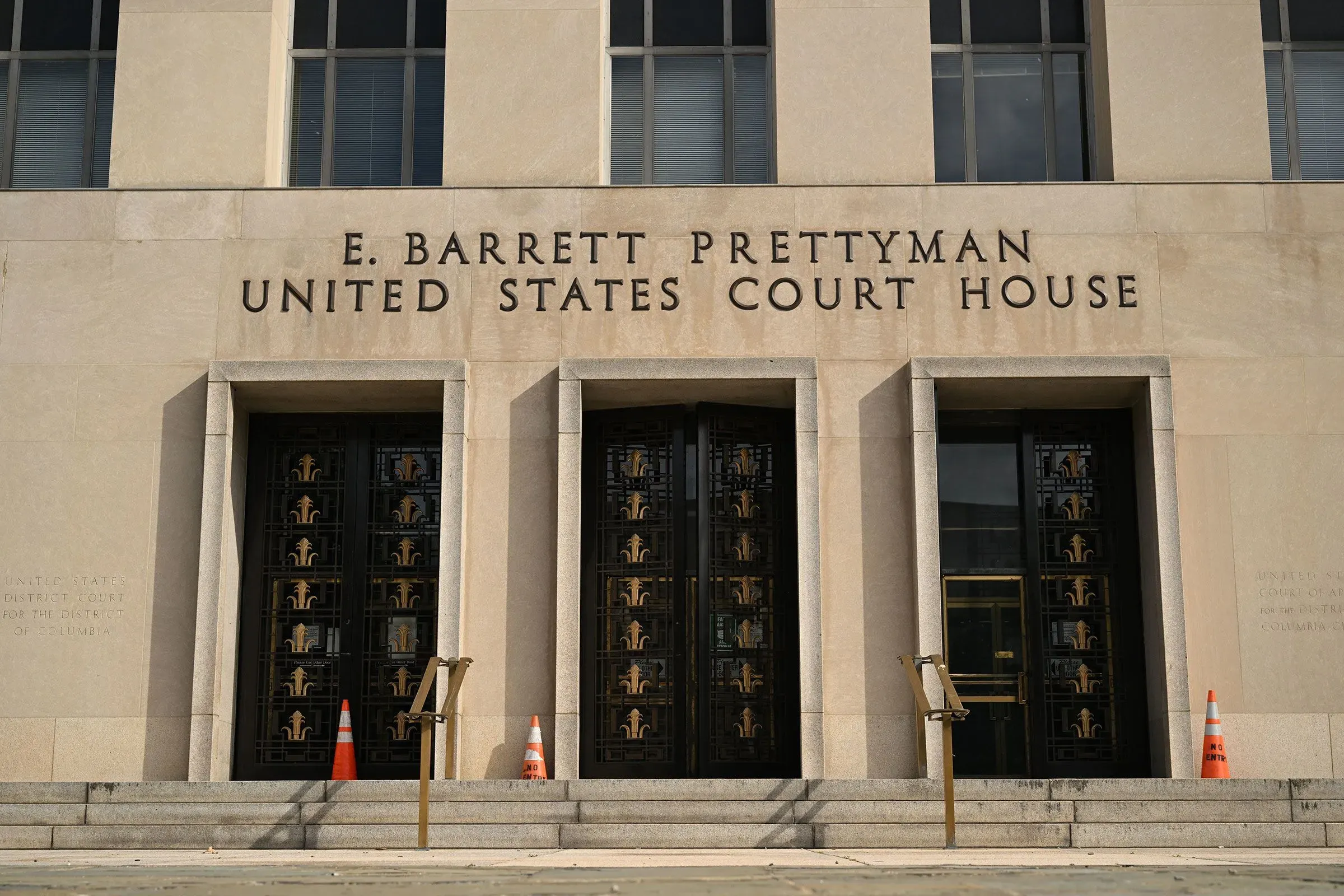 واجهة مبنى محكمة الولايات المتحدة، تحمل اسم "E. Barrett Prettyman"، مع أبواب زجاجية وأعمدة معمارية، تعكس أهمية النظام القضائي الفيدرالي.