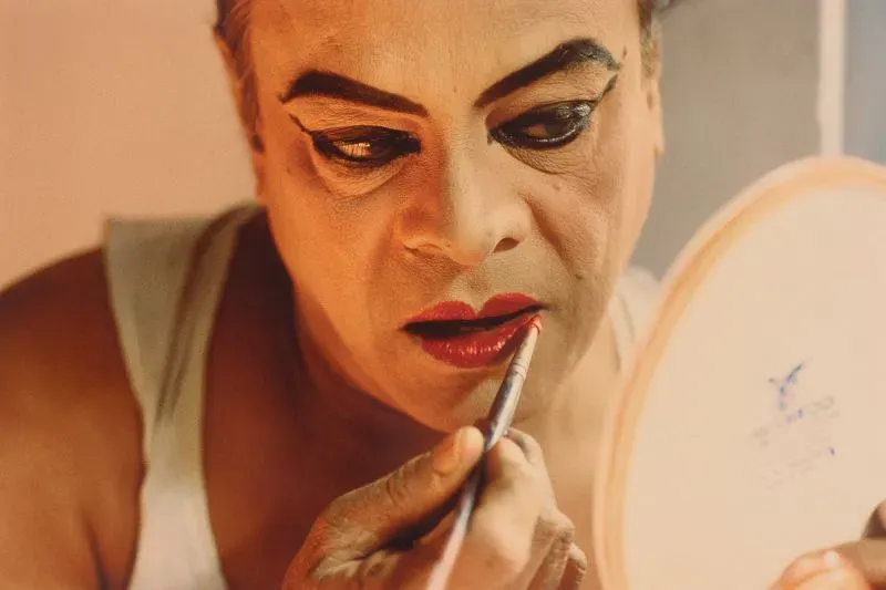 تشابال بهادوري يضع أحمر الشفاه أمام مرآة، مستعدًا لتجسيد شخصية إلهة هندوسية، مع التركيز على تفاصيل المكياج.
