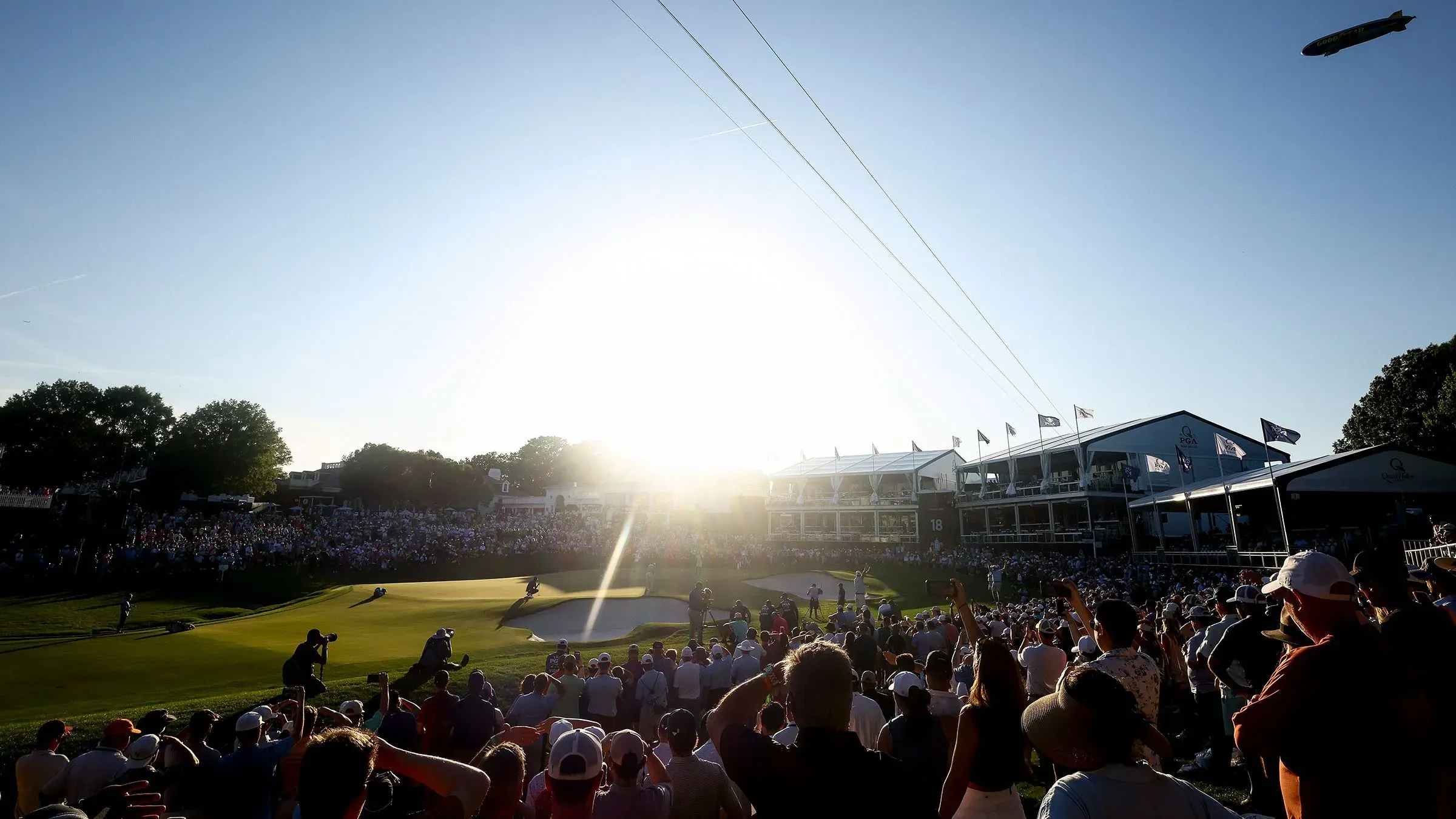 مشهد لجولة نهائية في بطولة الجولف بكويل هولو، حيث يتجمع الجمهور لمتابعة اللاعبين في الحفرة 18 تحت أشعة الشمس الساطعة.