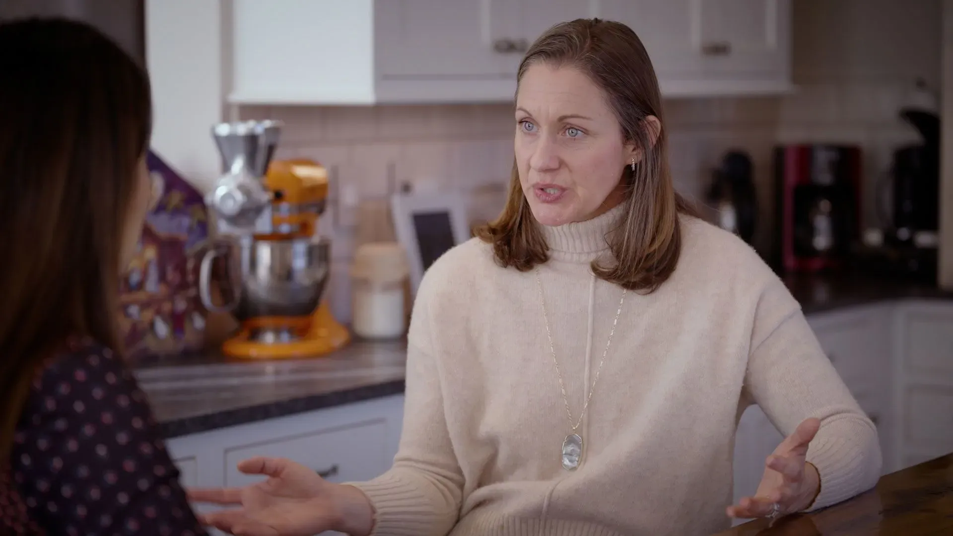 امرأة تتحدث في مطبخ، مع التركيز على موضوع تحديد النسل. تعكس المحادثة تباين الآراء حول وسائل منع الحمل الهرمونية.