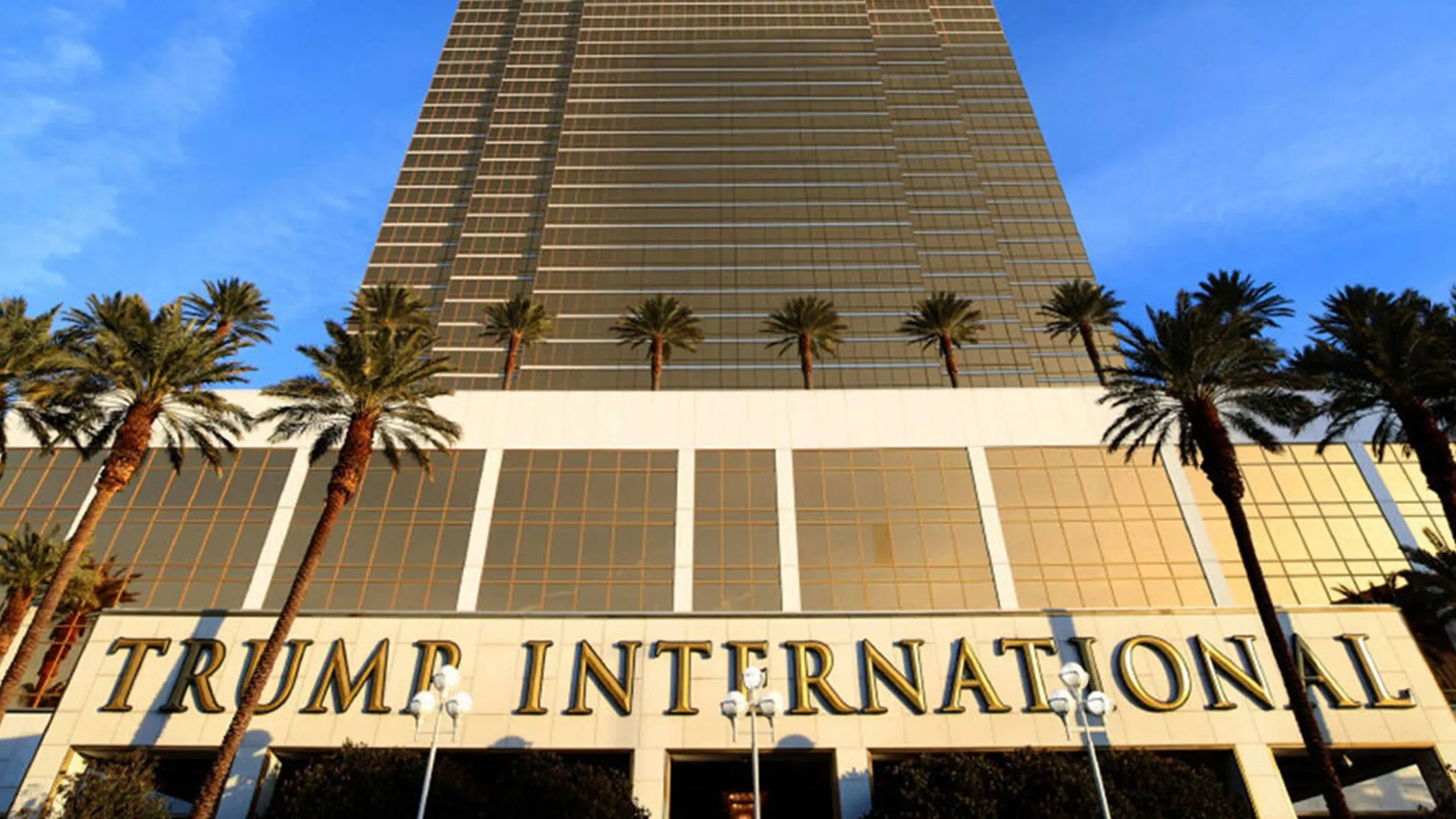 مبنى "ترامب إنترناشيونال" في لاس فيغاس، يتميز بواجهة زجاجية عاكسة وأشجار النخيل المحيطة، يعكس تأثير ترامب في عالم الأعمال.