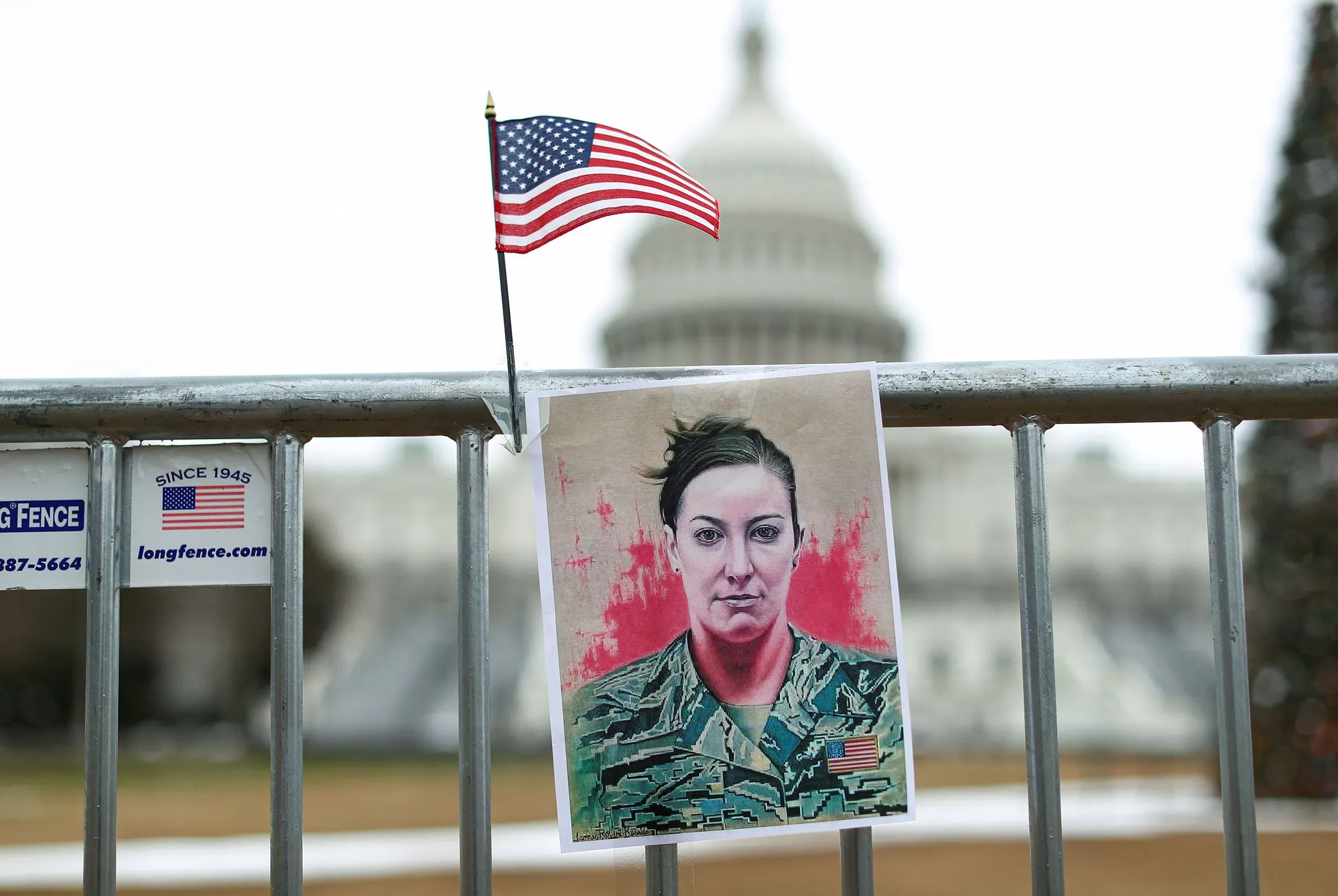 صورة لعلم أمريكي صغير ومؤسسة تحمل صورة آشلي بابيت، المحاربة السابقة في سلاح الجو، أمام مبنى الكابيتول، تذكير بأحداث 6 يناير 2021.