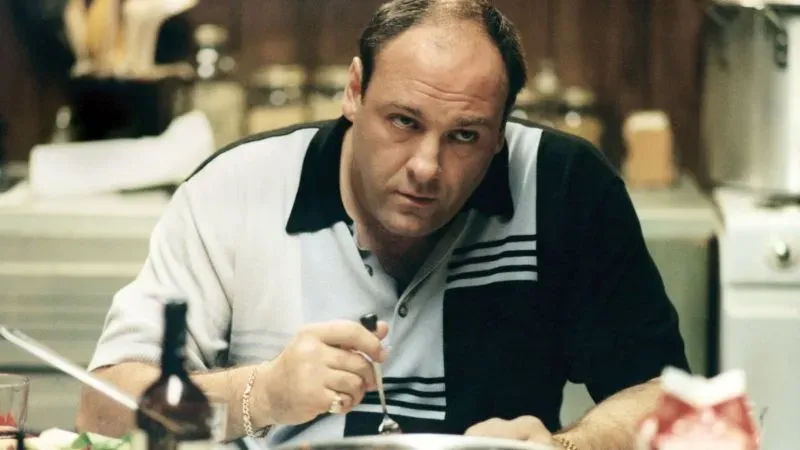 مشهد من مسلسل "ذا سوبرانوس" يظهر شخصية رئيس العصابة توني سوبرانو وهو يتناول الطعام، مما يعكس أجواء الحياة اليومية في المسلسل.