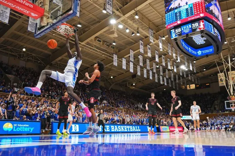 لاعب كرة السلة خامان مالواش يسجل نقطة من خلال سلة مرتفعة في مباراة بجامعة ديوك، وسط جمهور حماسي وأجواء تنافسية.