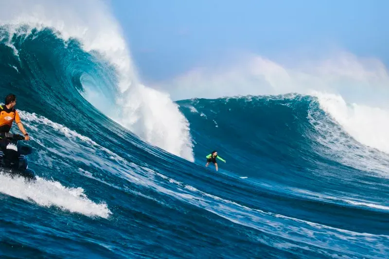 راكبة الأمواج لورا كرين تتزلج على موجة ضخمة في نازاري، البرتغال، بينما يتواجد سائق دراجة مائية بالقرب منها.