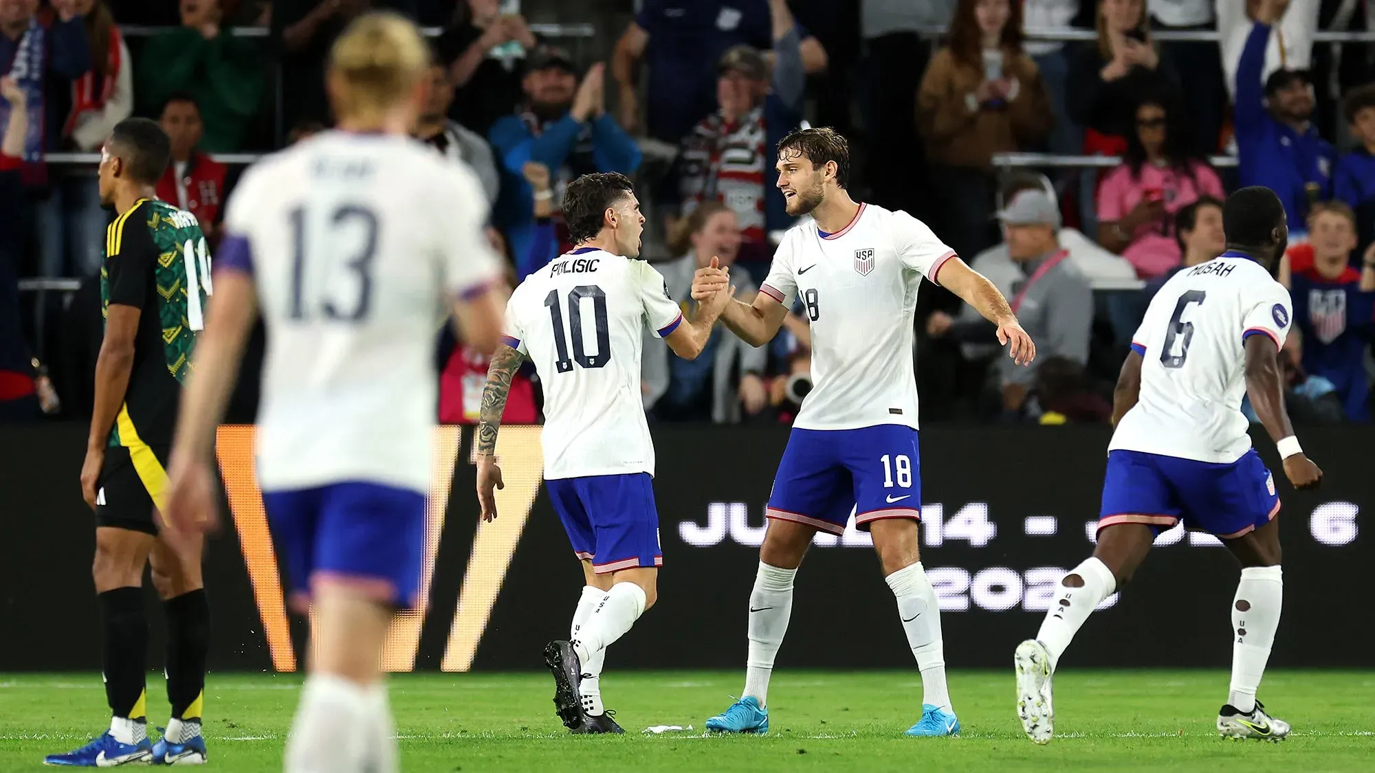 لاعبو المنتخب الأمريكي يحتفلون بعد تسجيل هدف خلال مباراة، وسط جمهور متحمس في الملعب، استعداداً لكأس العالم 2026.