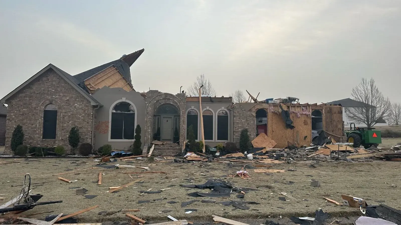 منزل عائلة دروب في أركنساس بعد تدميره بواسطة إعصار، حيث تظهر الأضرار الكبيرة في السقف والجدران، مع حطام متناثر في الفناء.