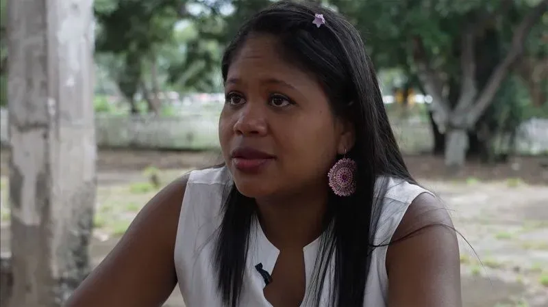 امرأة تتحدث بقلق في ورشة مهجورة في كالي، كولومبيا، تعكس تأثير إغلاق برامج المساعدات على المهاجرين الفنزويليين.