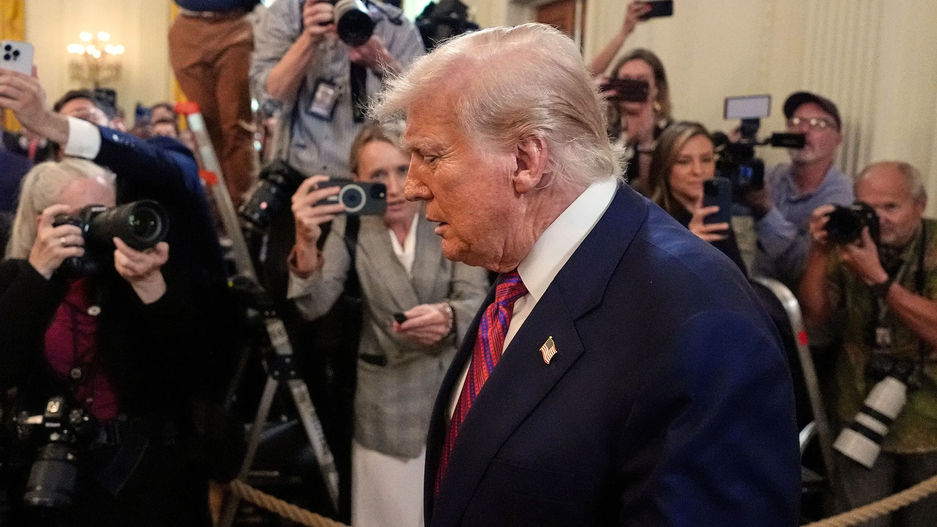 ترامب يسير وسط حشد من المصورين، مع تعبير جدي على وجهه، في سياق الجدل حول علاقته بجيفري إبشتاين.