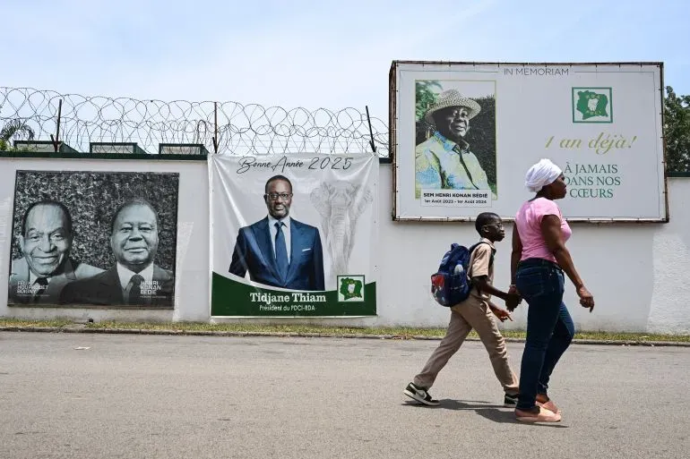 مؤيدو تيجان تيام يسيرون بجانب لافتات انتخابية في أبيدجان، مع تزايد التوترات السياسية قبل الانتخابات في ساحل العاج.