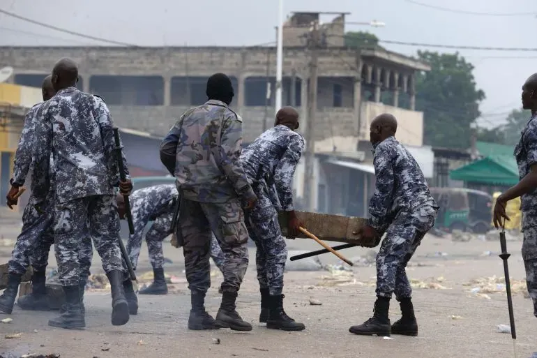 تظهر الصورة عناصر من قوات الأمن في توغو أثناء تدخلهم في الاحتجاجات، حيث يقومون بنقل حواجز. تعكس الأجواء التوتر السائد بعد الاضطرابات.