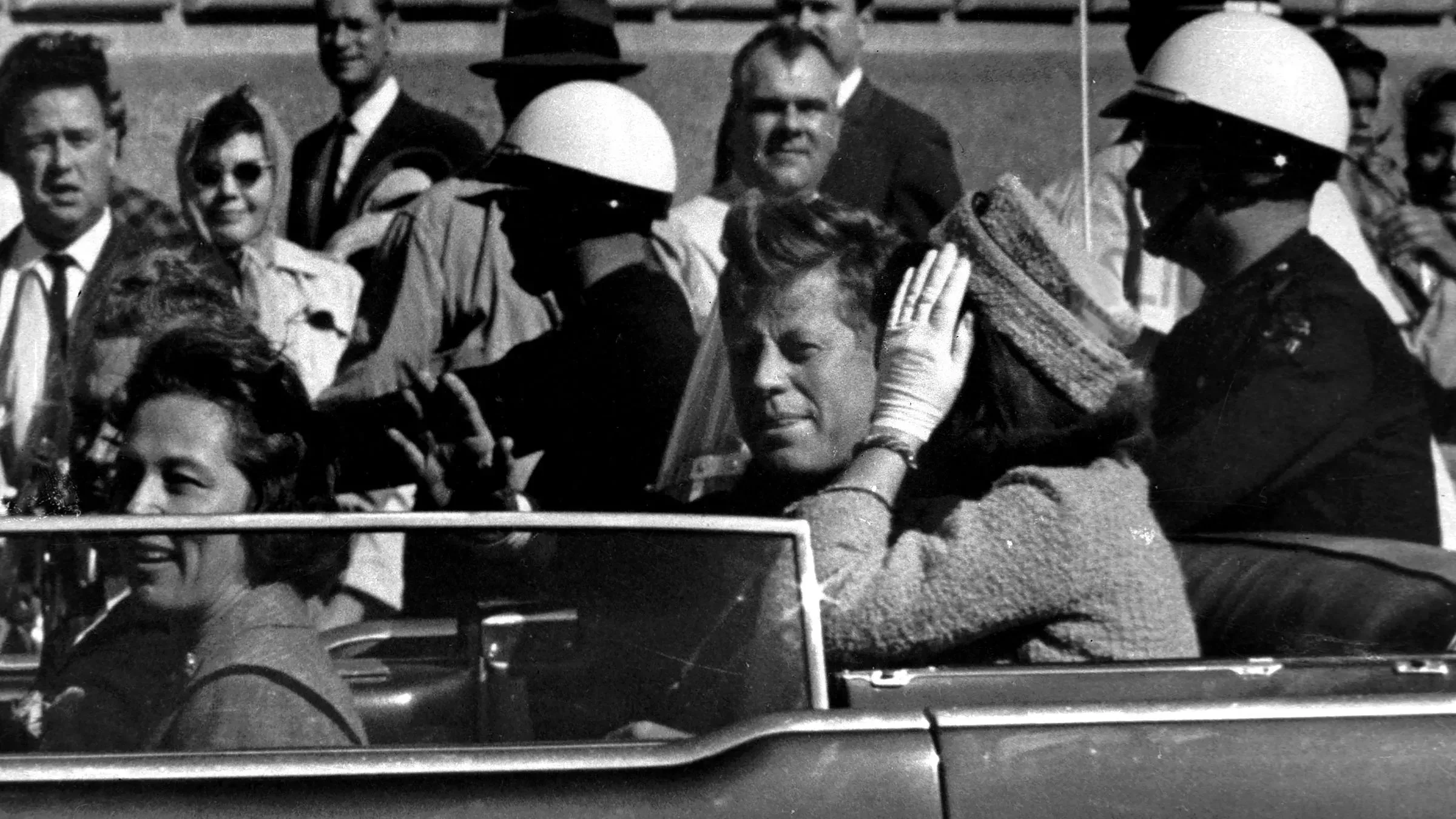 صورة تاريخية للرئيس جون كينيدي وزوجته جاكي خلال موكب في دالاس، قبل اغتياله عام 1963، تعكس اللحظة التي سبقت الحدث المأساوي.
