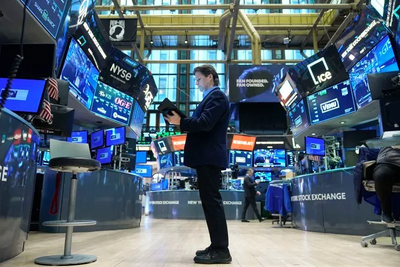 موظف في بورصة نيويورك يتفقد البيانات المالية على شاشات متعددة بينما تظهر علامات تجارية جيدة على الجدران، في سياق مخاوف من تأثير التعريفات الجمركية.