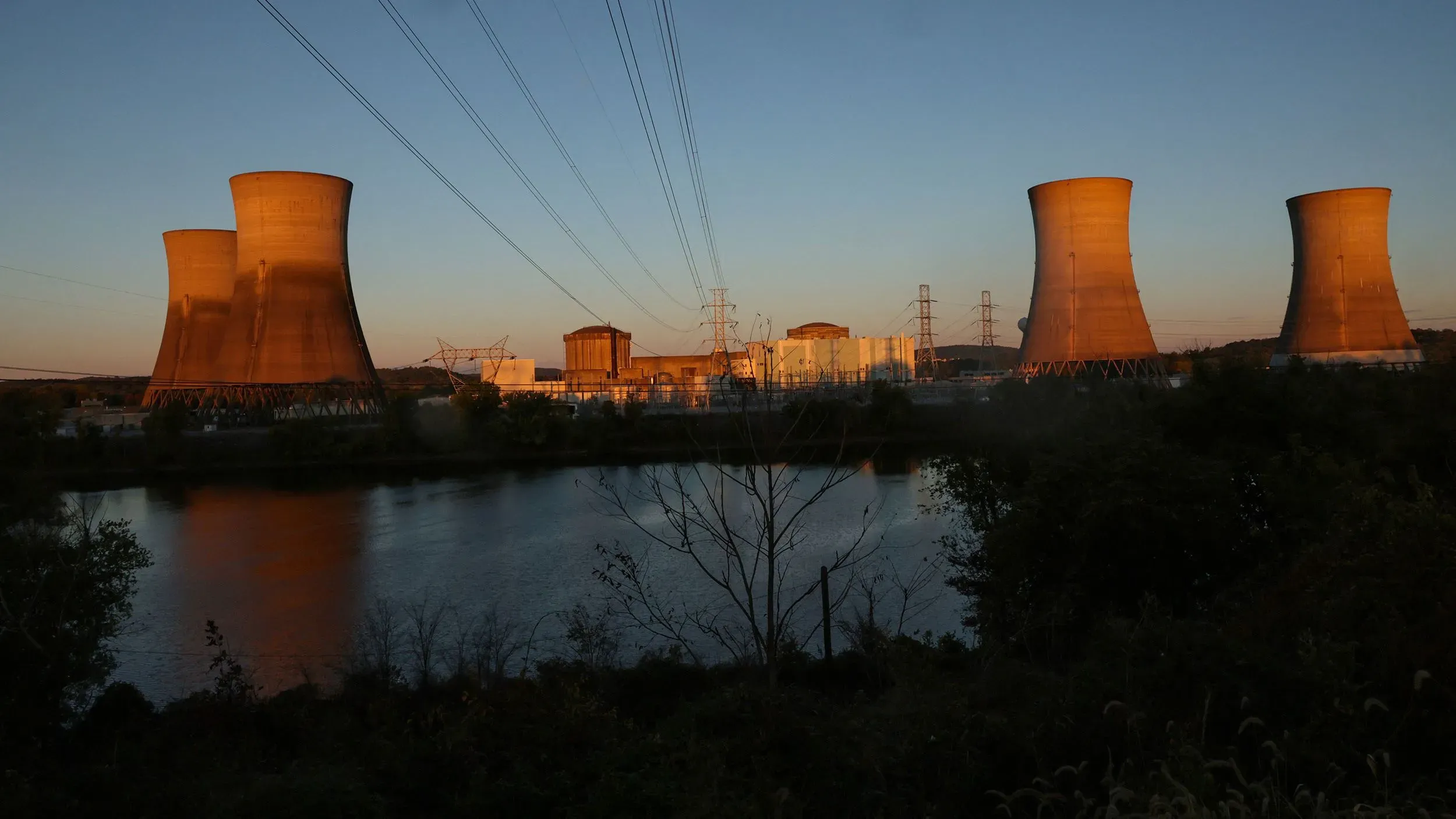 محطة طاقة نووية تظهر أبراج التبريد والمرافق المحيطة بها عند غروب الشمس، تعكس أهمية السلامة النووية والرقابة التنظيمية.