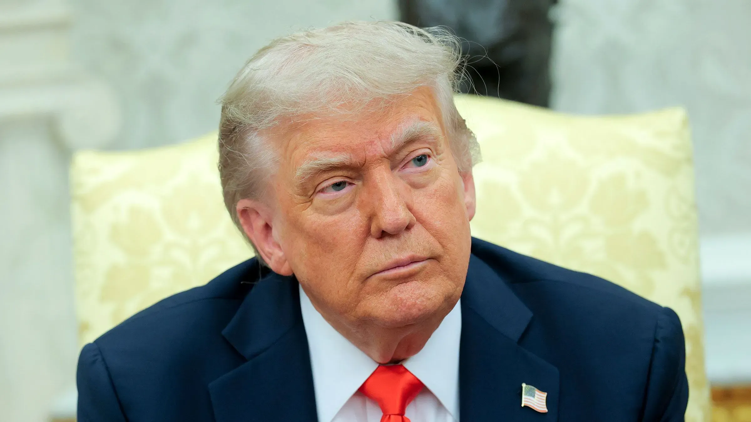 صورة لدونالد ترامب أثناء جلسة في المكتب البيضاوي، حيث يعكس تعبيره تركيزه على قضايا مالية تتعلق بأعماله المتنوعة، بما في ذلك العملات المشفرة.