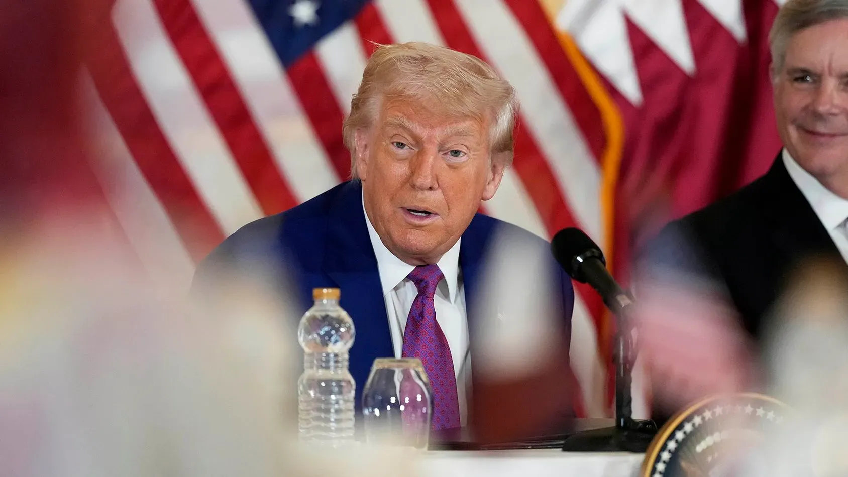 ترامب يتحدث خلال اجتماع في الدوحة، مع التركيز على قضايا الاتفاق النووي مع إيران، وخلفه علم الولايات المتحدة.