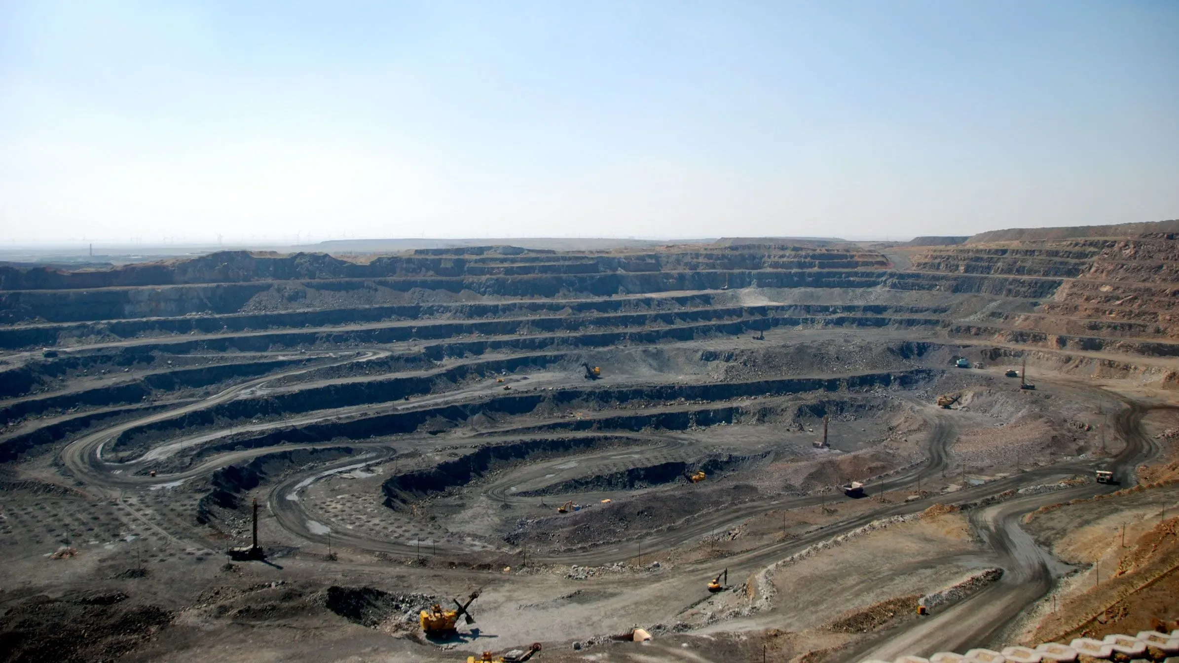 منجم كبير للمعادن الأرضية النادرة يظهر فيه طبقات عميقة من التربة مع معدات ثقيلة تعمل في الموقع، مما يعكس أهمية هذه الموارد في التجارة العالمية.