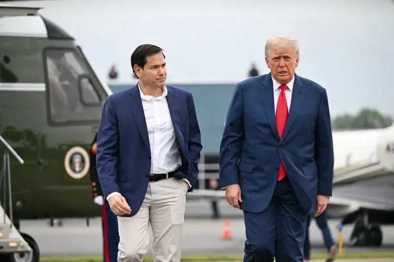 ترامب ومارك روبيو يسيران معًا بالقرب من طائرة هليكوبتر، تعبيرات وجههما تعكس أجواء سياسية مشحونة.