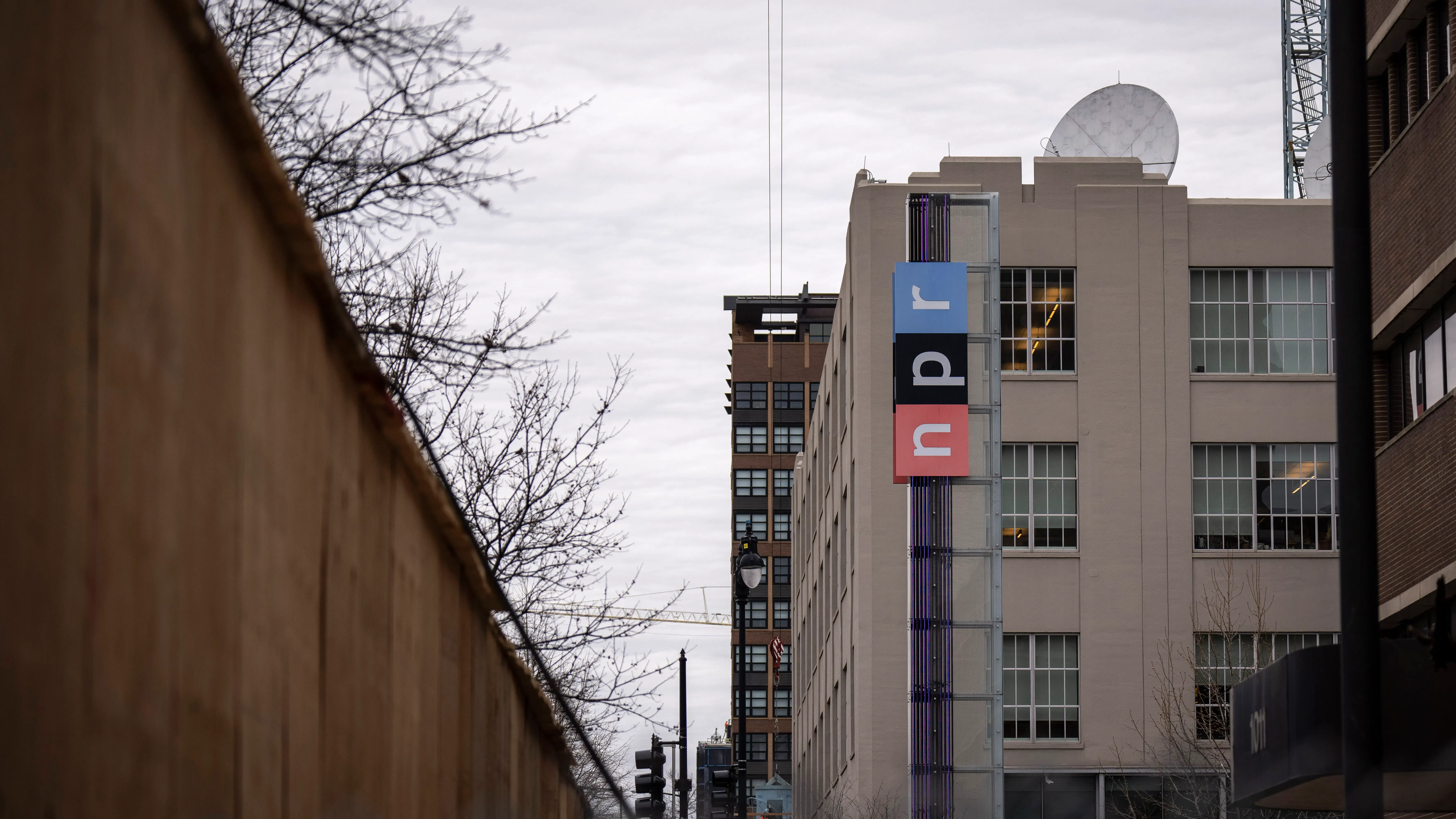 مبنى إذاعة NPR يظهر في الصورة، مع لافتة تحمل شعارها. تمثل الصورة سياق التحقيق الفيدرالي في ممارسات الإعلانات الخاصة بالإذاعة.