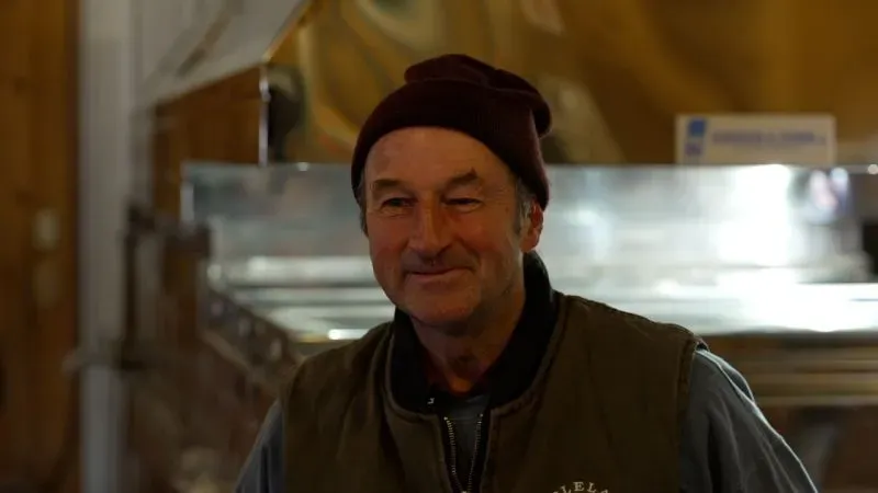 كيفن كيز، مالك دار دراي بروك للسكر، مبتسم أثناء عرض معدات إنتاج شراب القيقب، وسط أجواء مزارع القيقب في نيويورك.